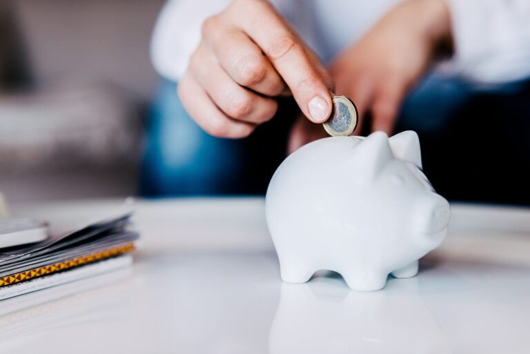 Woman Putting Coin In Piggy Bank